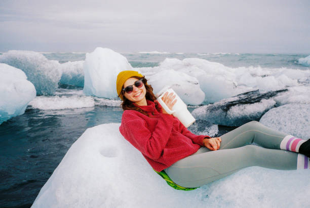 Woman sunbathing laying on iceberg on the beach in Iceland