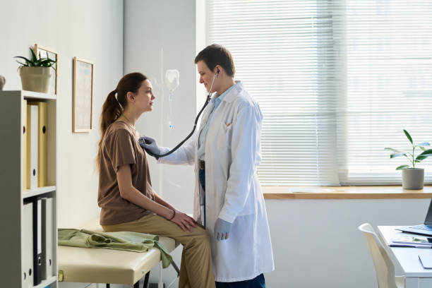 istock Doctor Examining Patient with Stethoscope in Office 2169401884