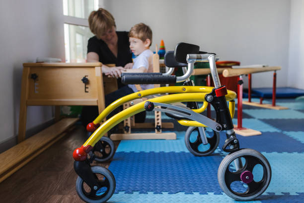 istock Cute boy with neurodevelopmental disorders is participating in a rehabilitation session under guidance of therapist in therapy space with rehab walker 2169405009