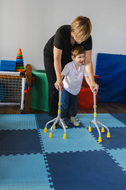 istock Physical therapist assists a young boy with cerebral palsy as he practices walking using specialized equipment in rehabilitation setting 2169405025