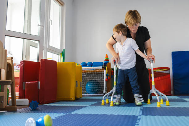 istock Cute young boy with cerebral palsy works with a therapist on physical rehabilitation using rehab bariatric 4-point canes in therapy center 2169405045