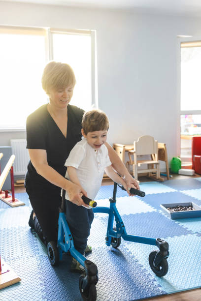 istock Physical therapist assists a young boy with movement disorders as he engages in physical rehabilitation using a walker in a bright therapy room 2169405050