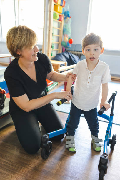 istock Physiotherapist assists a young boy with musculoskeletal disorders using mobility aids during rehabilitation exercises in a supportive environment 2169405057