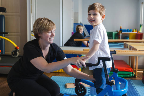 istock Bobath therapist assists a young boy with cerebral palsy as he practices using a supportive mobility device during a session 2169405065