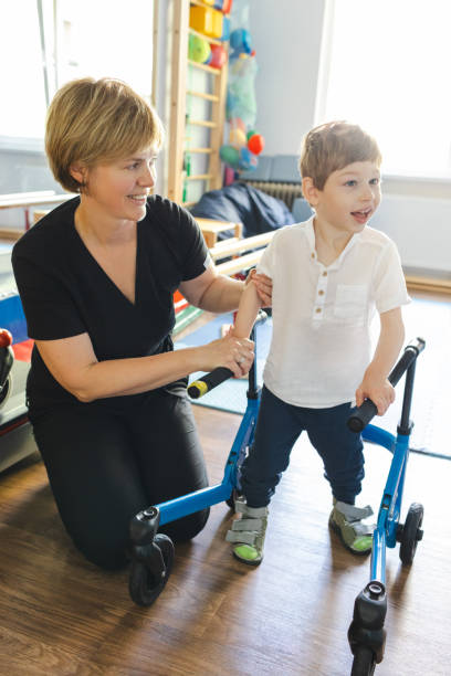 istock Physical therapist assists a young boy with cerebral palsy using a walker during his rehabilitation session in a sunny, cheerful environment 2169405067