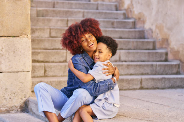 istock A mother and child are sitting on a step, hugging. The scene is warm and affectionate 2169408359