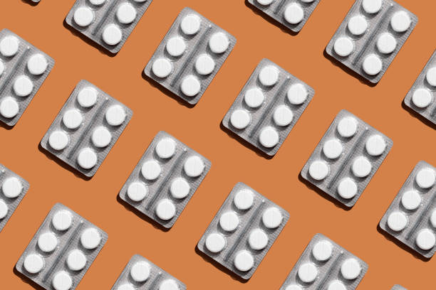 istock Pattern of blister pack with six round white tablets on orange background, creating a visually striking geometric layout. Creative pills concept 2169411051