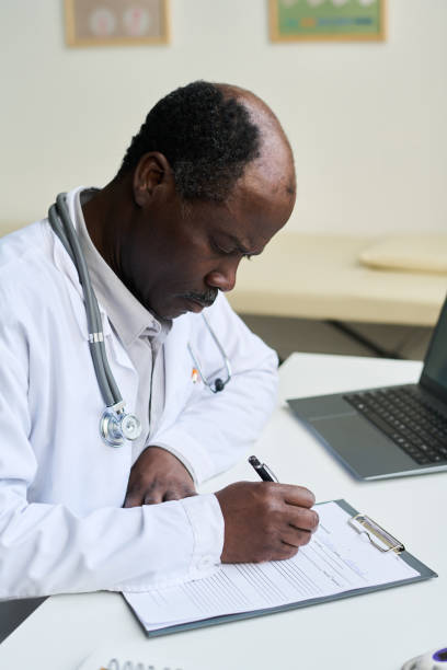 istock Writing Medical Notes in Doctor's Office by African American 2169413671