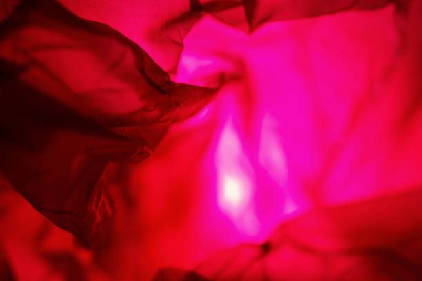 Extreme close up of red empty plastic bag background. The plastic surface is wrinkly and tattered making abstract pattern. Selective focus, shallow depth of field.