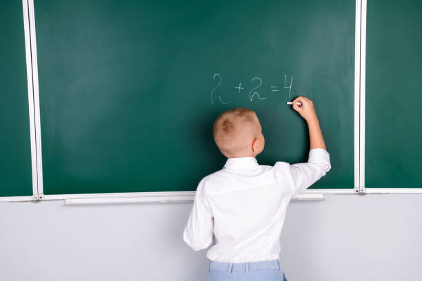 istock Photo of clever diligent boy in class room solve write math task isolated on green board background 2169420579