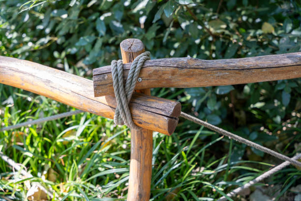 Wooden fence secured with rope. The fence is surrounded by green grass.