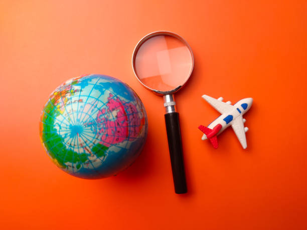 istock Top view earth globe,magnifying glass and air plane on a orange background 2169423166