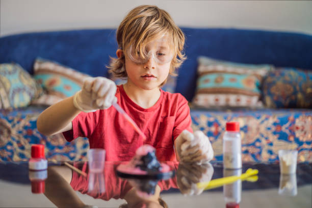 istock Kid boy doing chemical experiment at home. Child with protective glasses study using pipette dropping liquid to test tube, caucasian, biochemistry. chemistry class. home school concept 2169427674