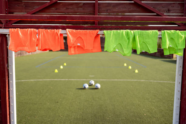 Green artificial turf football field with blurred athletes. Football players training on outdoor green artificial turf field. Abstract background. Mock up for montage product display or design your products. Summer sport.