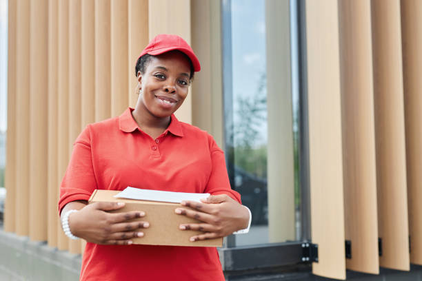 istock Smiling Woman Holding Package while Wearing Red Uniform 2169432680