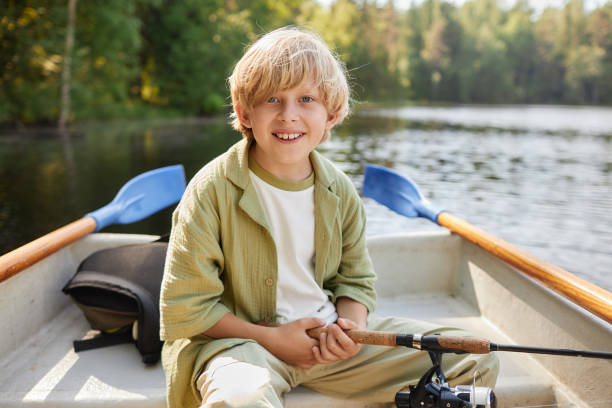 istock Smiling Boy Rowing on Tranquil Lake in Morning Sunlight 2169434095