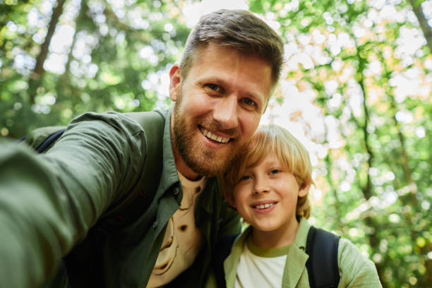 Smiling Father and Son Taking Nature Selfie in Forest