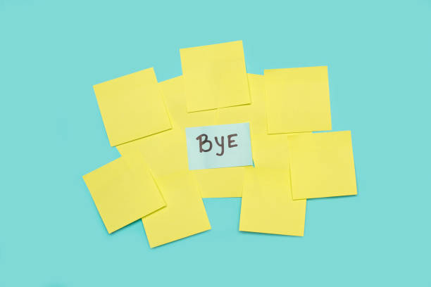 Bye single word handwritten on a light blue sticky paper on yellow blank sticky papers on a light blue background