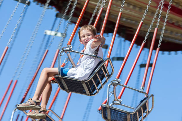 istock Happy boy rides on a chain carousel and waves his hand. 2169438844