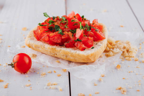 istock Delicious bruschetta with chopped tomatoes and basil resting on paper on white table 2169439571