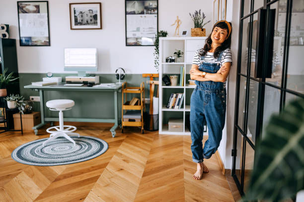 istock Casually clothed beautiful smiling woman posing while leaning on glass wall at home 2169442629
