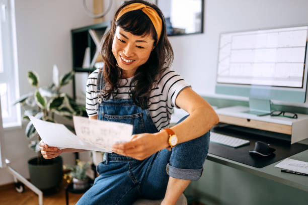 istock Smiling beautiful Japanese woman analysing paperwork while working at home office 2169442674