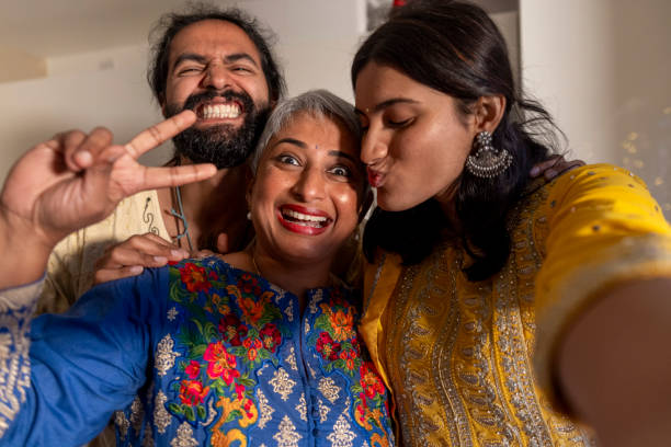 Close up view of a small group of family and friends celebrating Diwali in a family home in Newcastle, England. Some guests are wearing traditional Indian clothing. They are standing side by side taking a selfie on a smartphone.\n\nVideos similar to this scenario also available.
