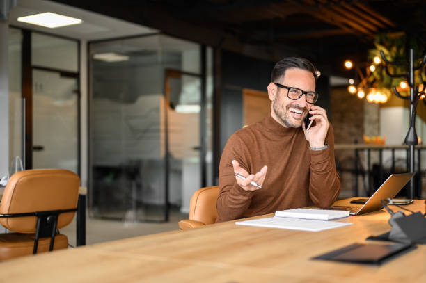 istock Handsome manager discussing over phone call while working on project over laptop at his workplace 2169448280