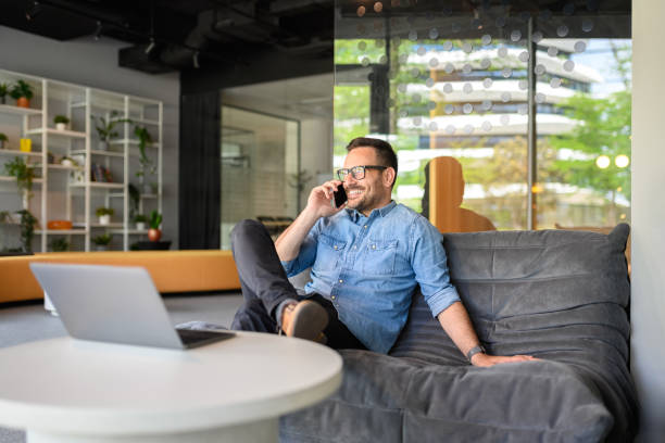 istock Confident sales manager discussing over phone call while sitting on comfortable sofa at his workplace 2169448344