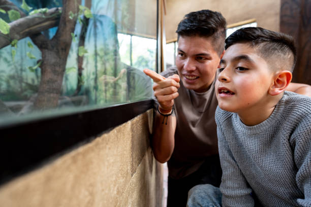 istock Father and son with physical disability looking at aquarium 2169448491