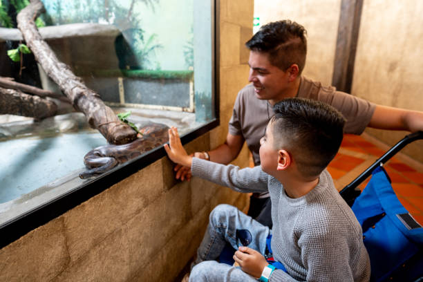 Father and son with physical disability looking at aquarium