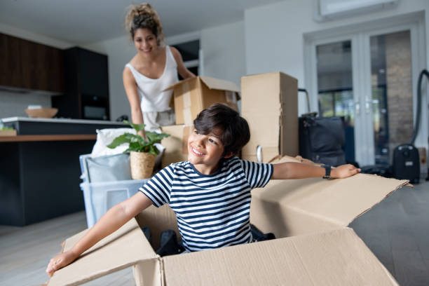 istock Happy boy playing in a box while moving house with his family 2169450233