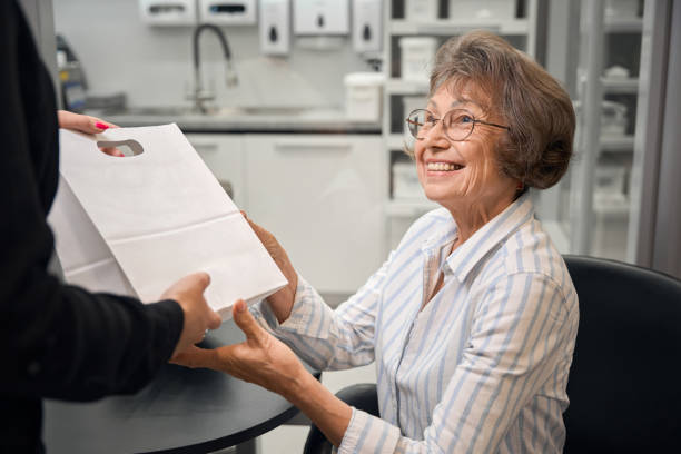 istock Smiling lady receives gift bag from clinic administrator 2169451723