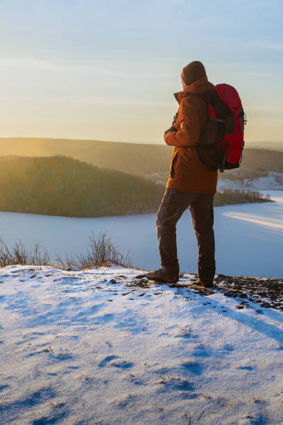istock A man with a backpack is standing and looking out at the beautiful sunset. 2169453179