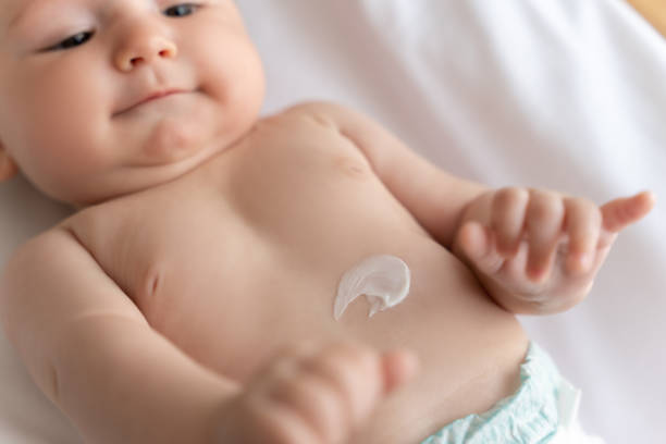 istock Infant child with lotion on his belly lying on white sheet 2169453390