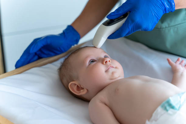 istock Doctor's hand holding thermometer at the child's forehead and measures his temperature 2169453547