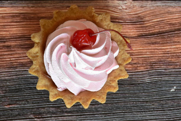 Cherry tartlet cake with protein cream on wooden table background. Delicious dessert, shortcrust pastry. Top view.
