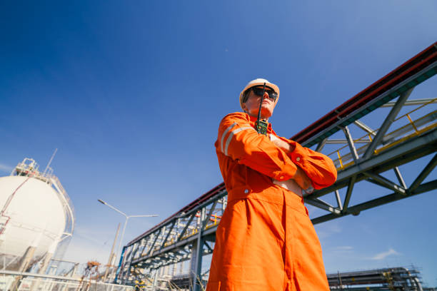 istock A professional engineer in protective gear, including a hard hat and orange coveralls, inspects a large industrial facility. The image highlights the importance of safety and expertise in the engineering field. 2169456983