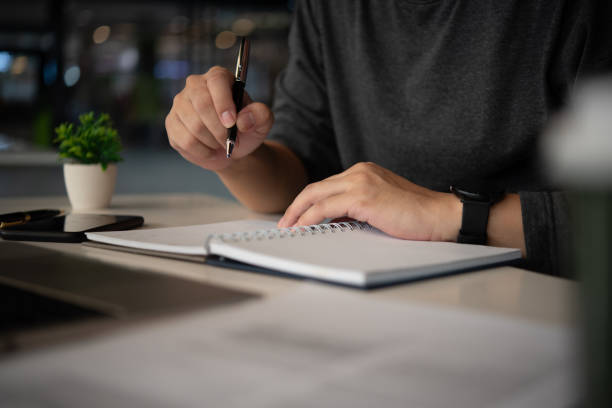 istock person writing notes in a notebook in an office setting, capturing the process of planning, brainstorming, and documenting strategies in business operations. 2169462148