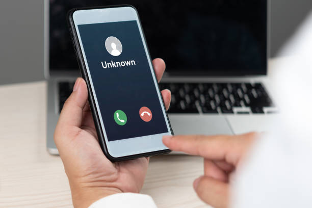 istock hand holding a smartphone displaying an incoming call from an unknown caller, representing communication, security risks, and mobile technology. 2169462276