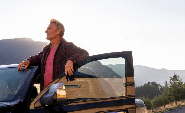 istock Senior man looks at mountains from vehicle 2169464194