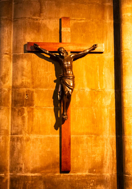 A figure of Jesus Christ on the Cross, lit in a fiery light, on the wall of the church of St Bartholomew the Great in Smithfield, City of London. The church, near the famous St Bartholomew’s Hospital, was founded in 1123 as an Augustinian Priory and both were founded by Rahere following a vision whilst at the Vatican that he should erect a church in Smithfield.
