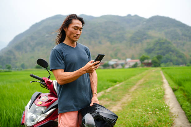 istock Man on motorcycle using cell phone  at Mai Chau Valley 2169475715