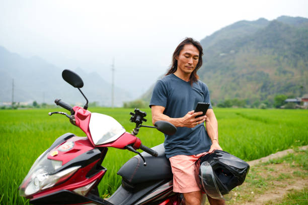 istock Man on motorcycle using cell phone  at Mai Chau Valley 2169475736