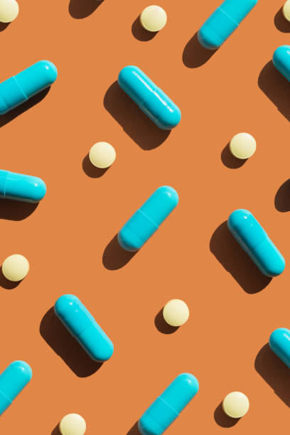 istock Pattern of blue and yellow pills on orange background. Creative tablets concept 2169476288