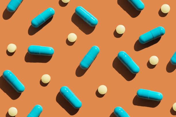 istock Pattern of blue and yellow pills on orange background. Creative tablets concept 2169476314