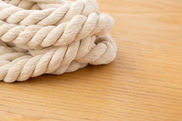 A coiled natural fiber rope placed on a smooth white surface. Ideal for crafting and DIY projects, showcasing a soft and rustic texture for artistic designs.