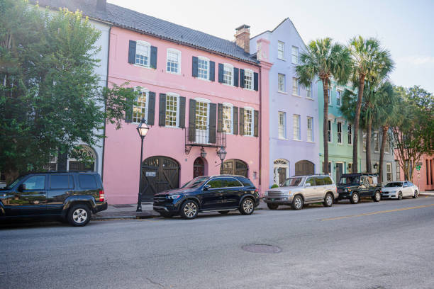 Charleston, South Carolina - May 7, 2024:  The famous Rainbow Row in Charleston, with a long cluster of Georgian row houses with pastel colors on the East Bay Street.  Out of focus tourists in pastel colored dresses complementing to the composition.  HDR encoded.