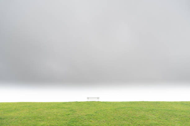 Minimalistic shot of a bench on a dyke under a dramatic cloudy sky
