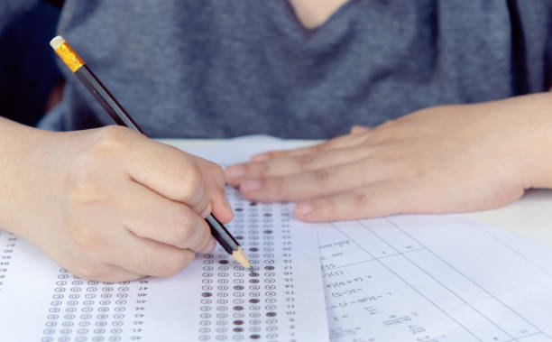 istock Students hand holding pencil writing selected choice on answer sheets and Mathematics question sheets. students testing doing examination. school exam 2169489022